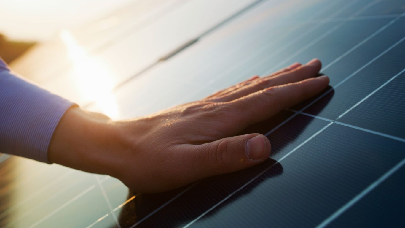 Käsi koskettaa aurinkopaneelia
