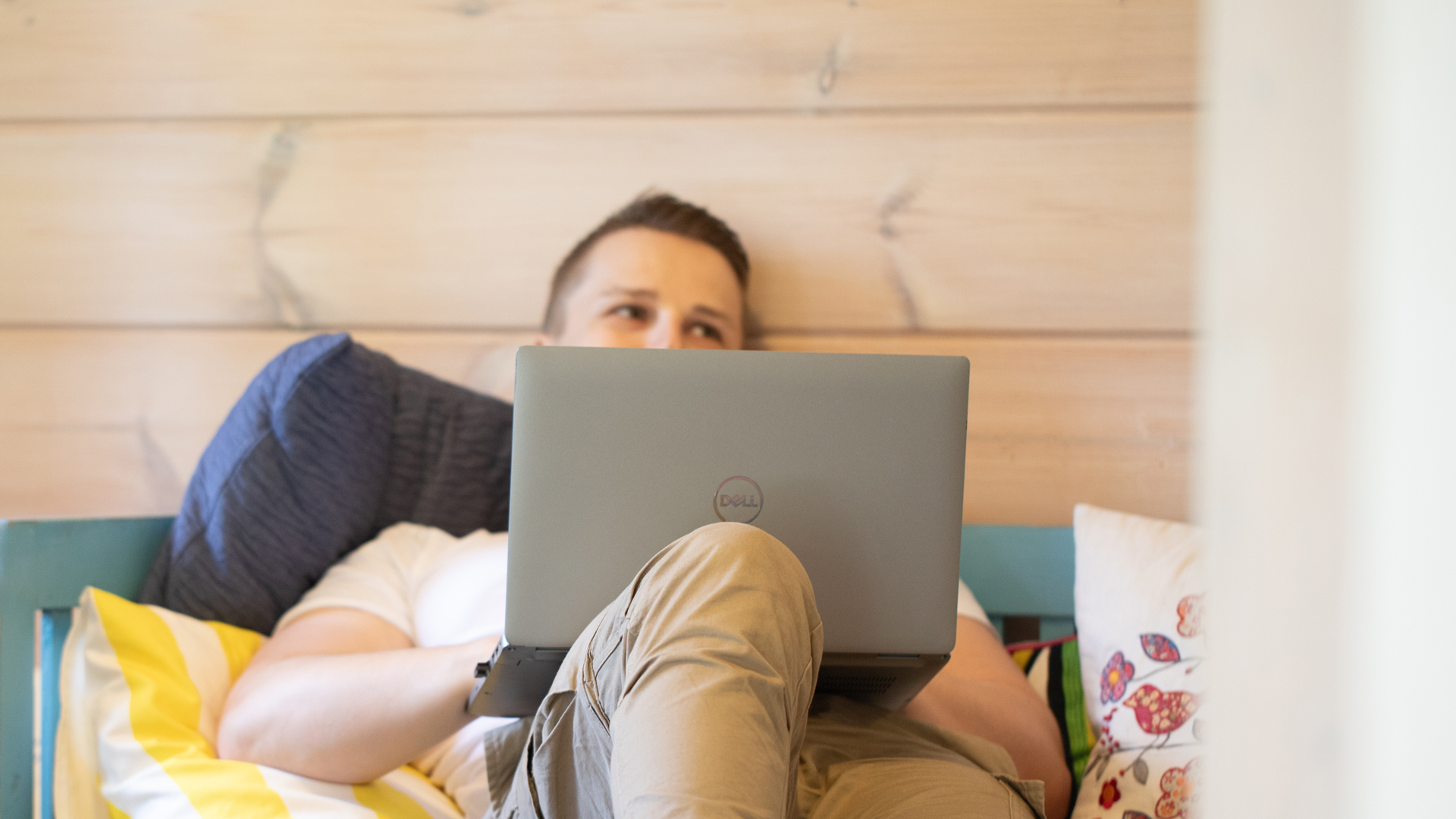 Mies on tietokoneella sohvalla.