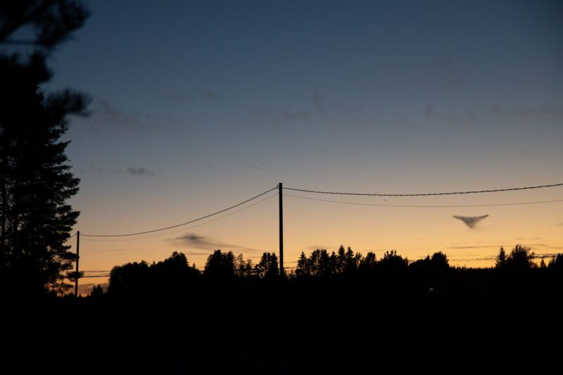 Sähkölinja menee metsän läpi auringonlaskussa.