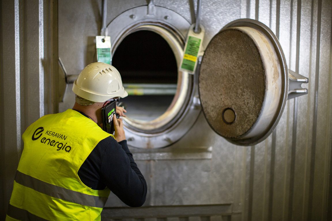 Työntekijä puhuu puhelimessa ja tekee töitä voimalaitoksella.