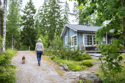 En kvinna och en hund går i skogen.